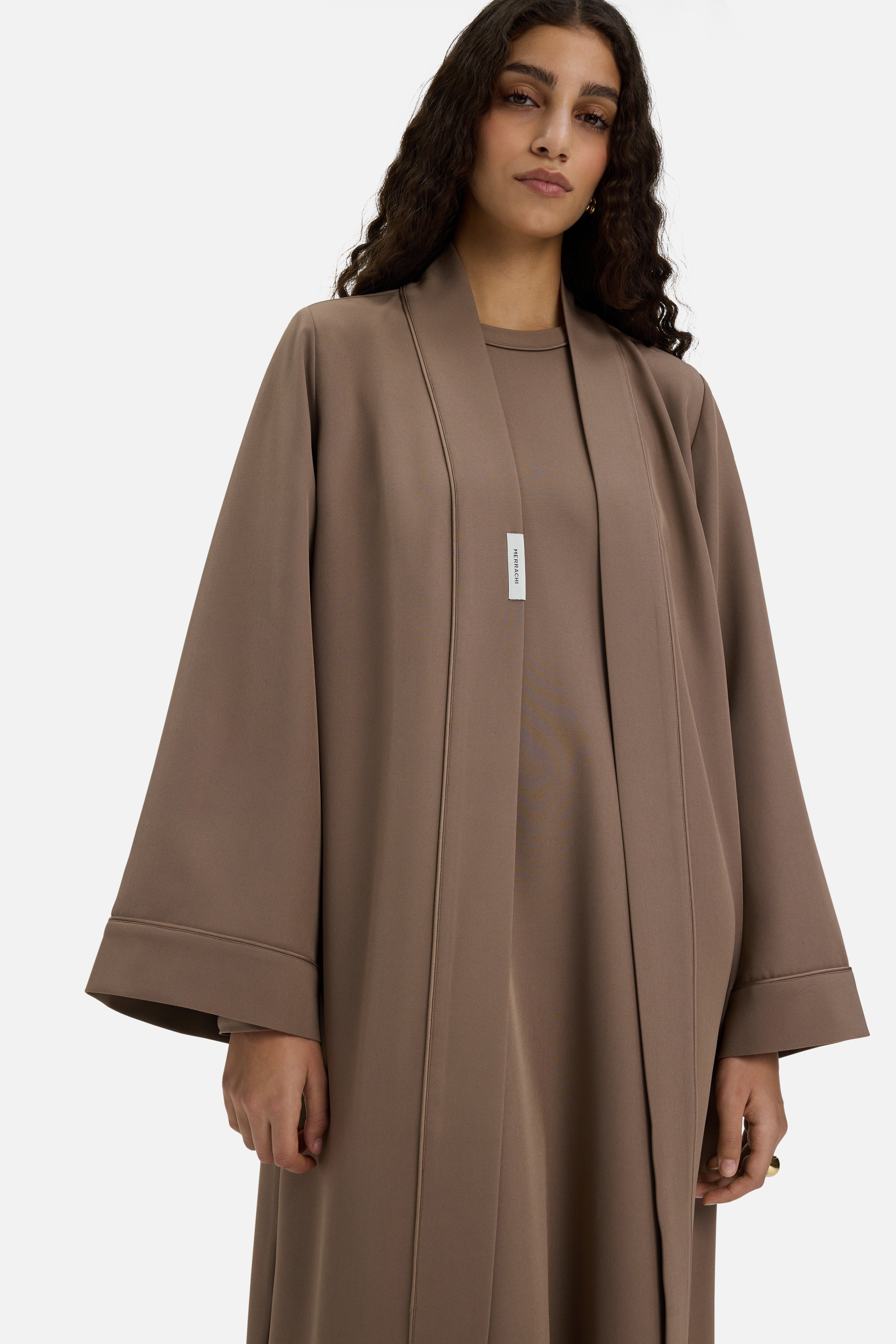Cropped front view model wearing taupe MERRACHI abaya