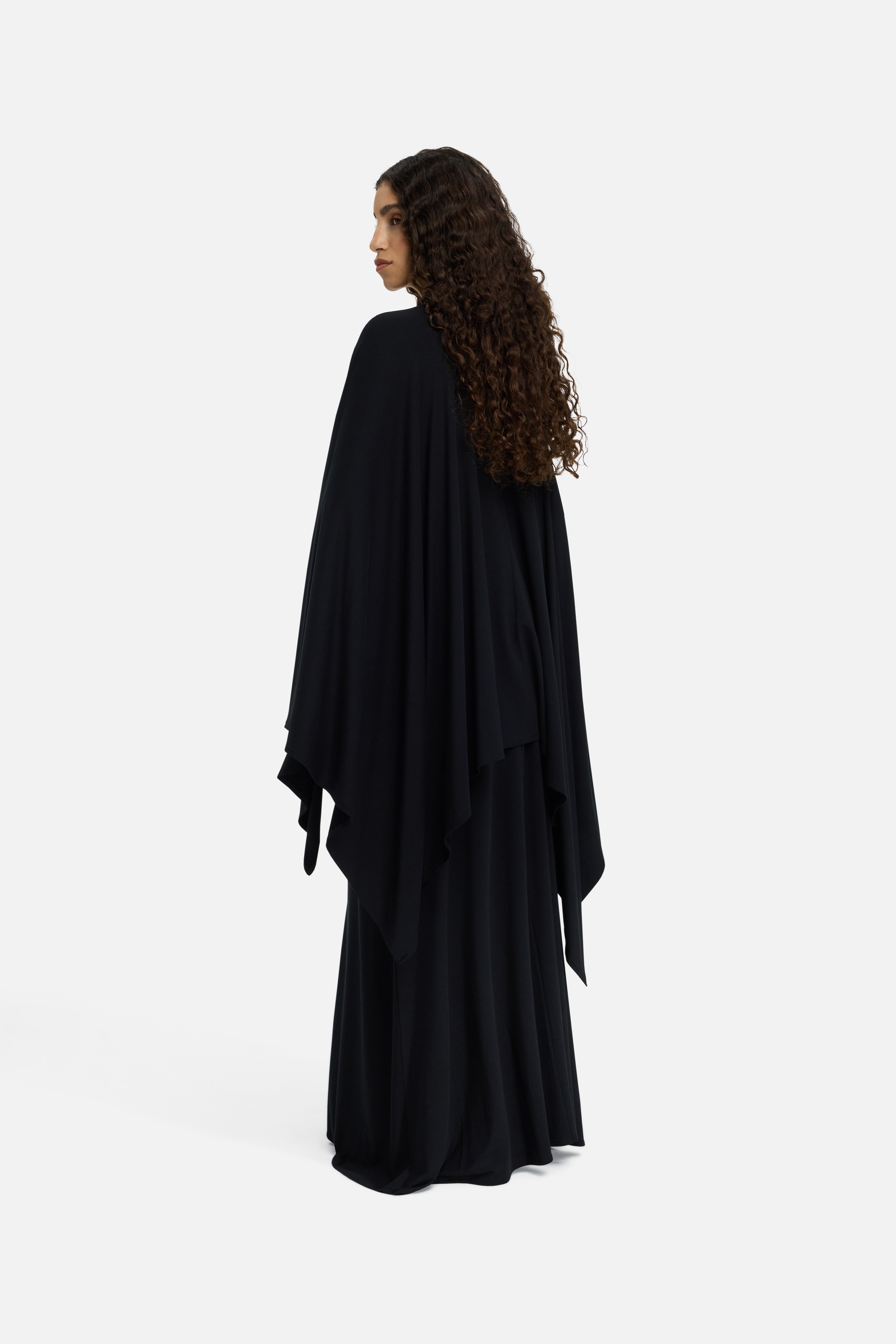 Model wearing black MERRACHI cape, back view