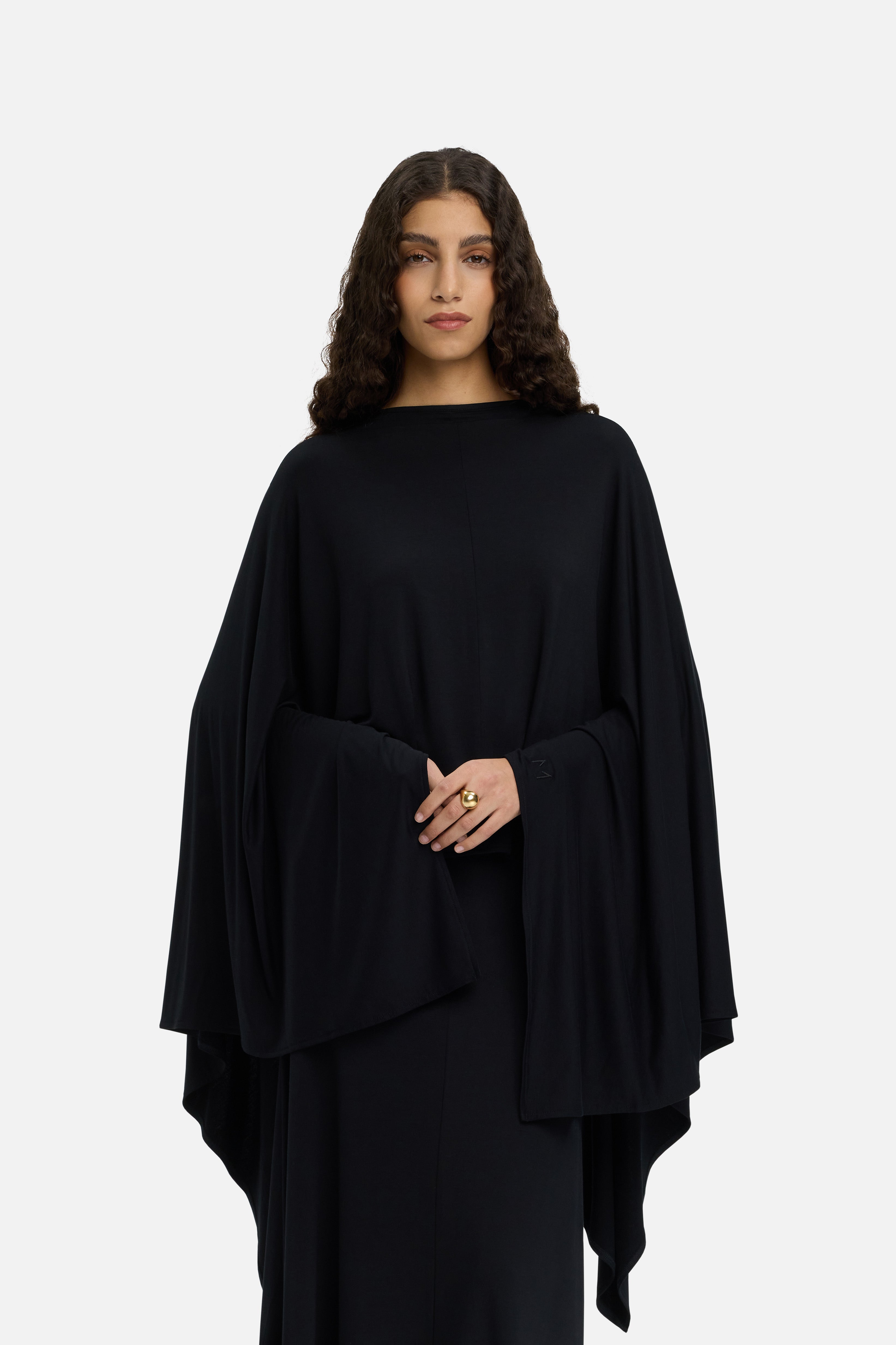 Model wearing black MERRACHI cape, cropped front view