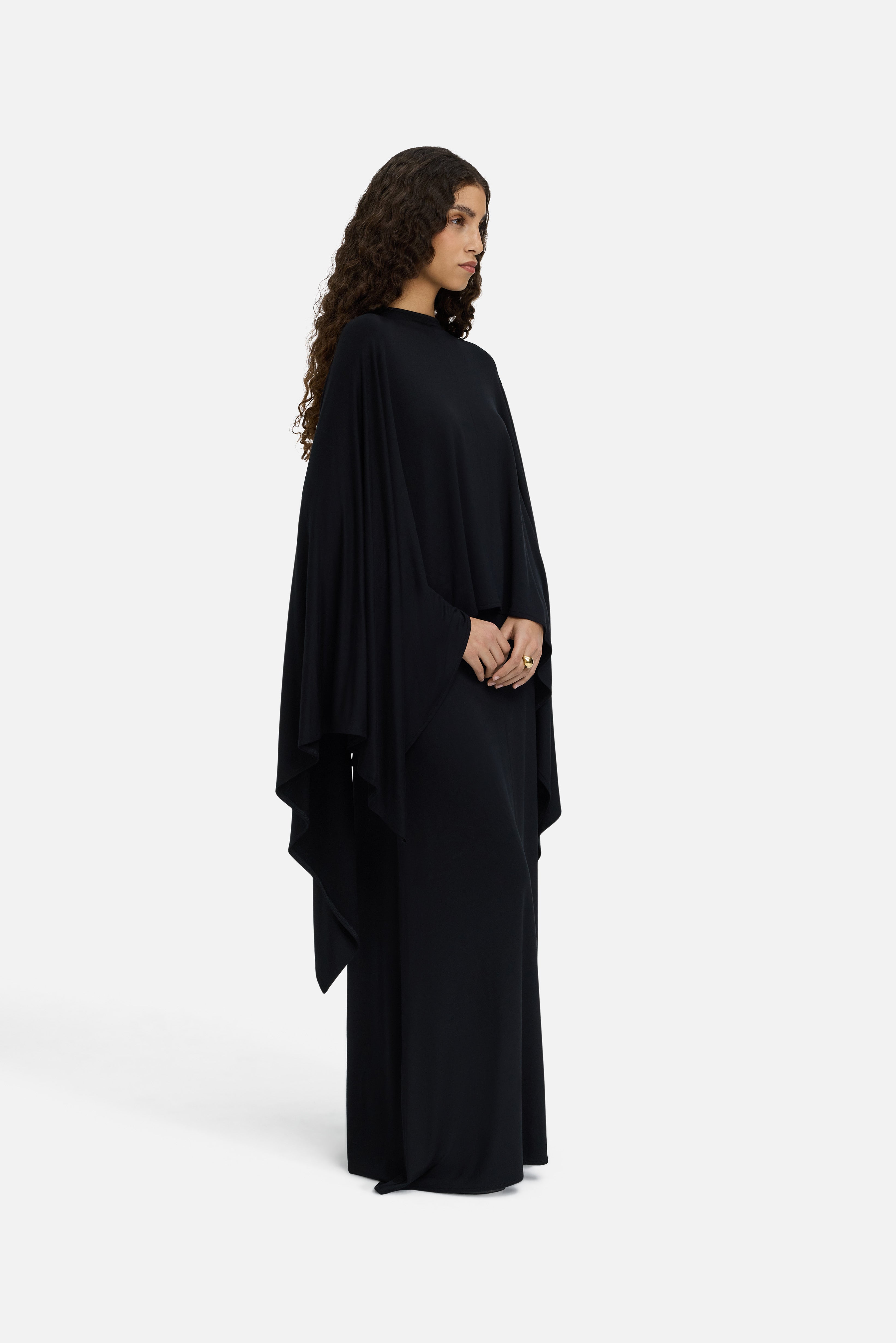 Model wearing black MERRACHI cape, side view