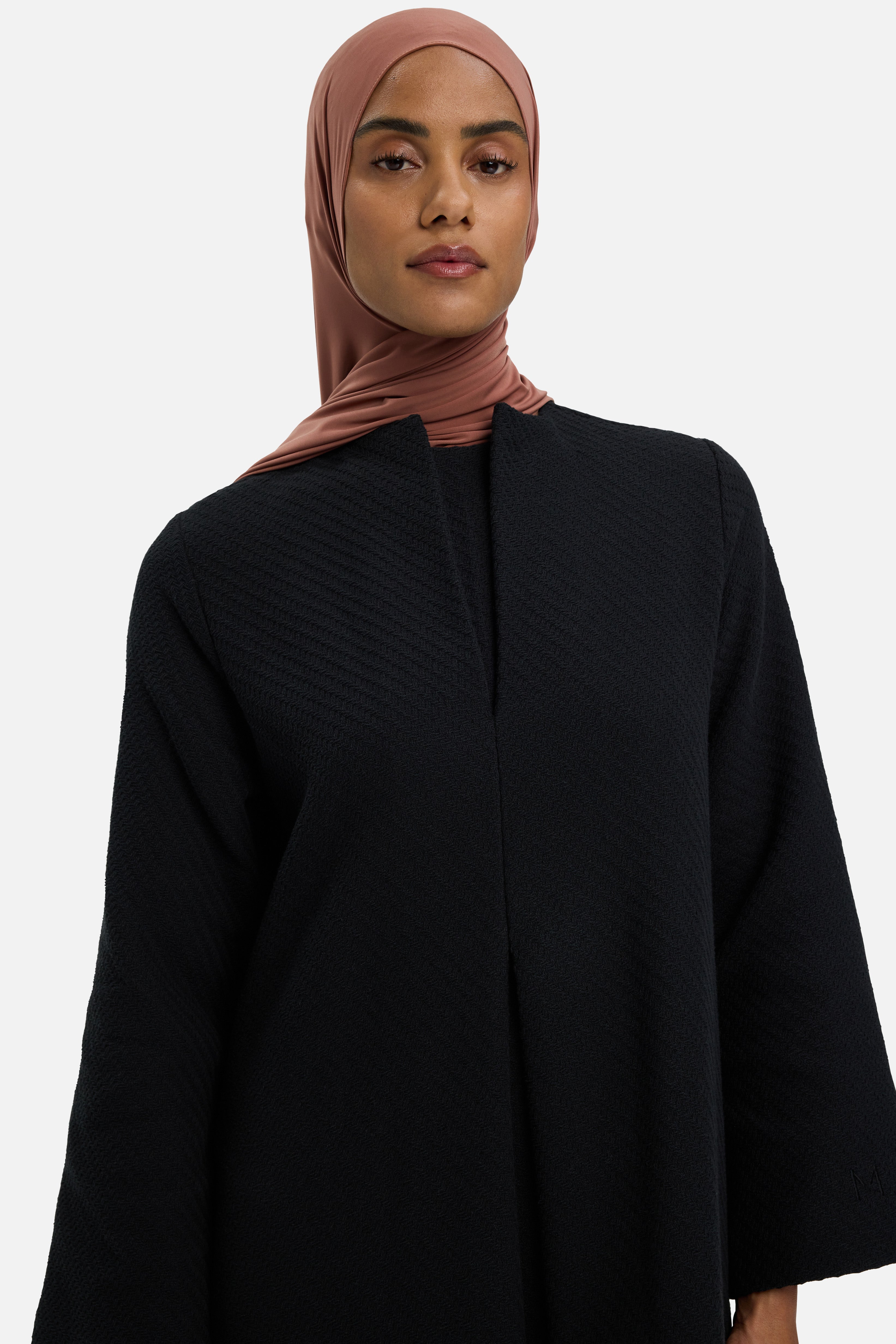 Close up model wearing black dress and pink headscarf