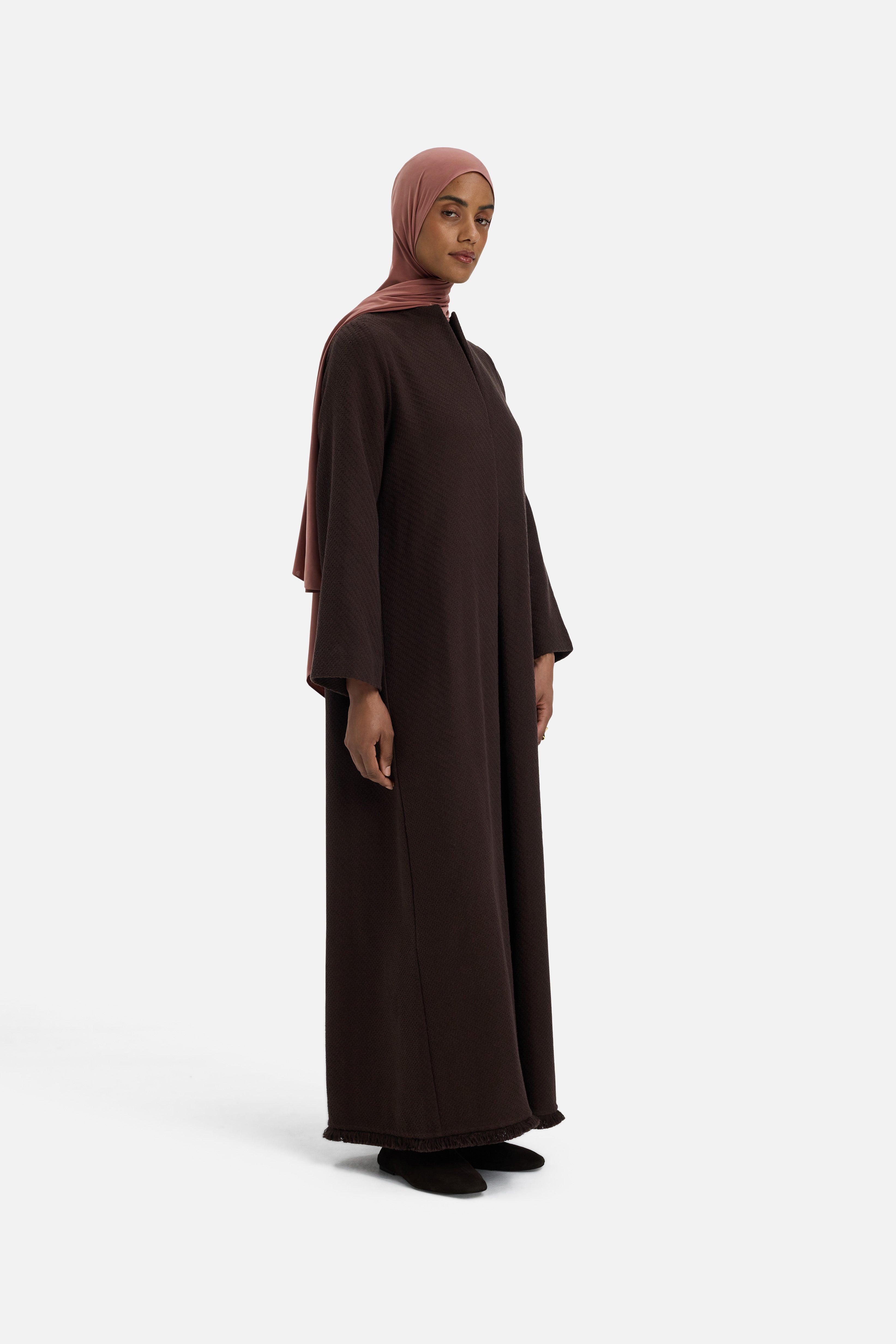 Side view model wearing dark brown dress and pink headscarf