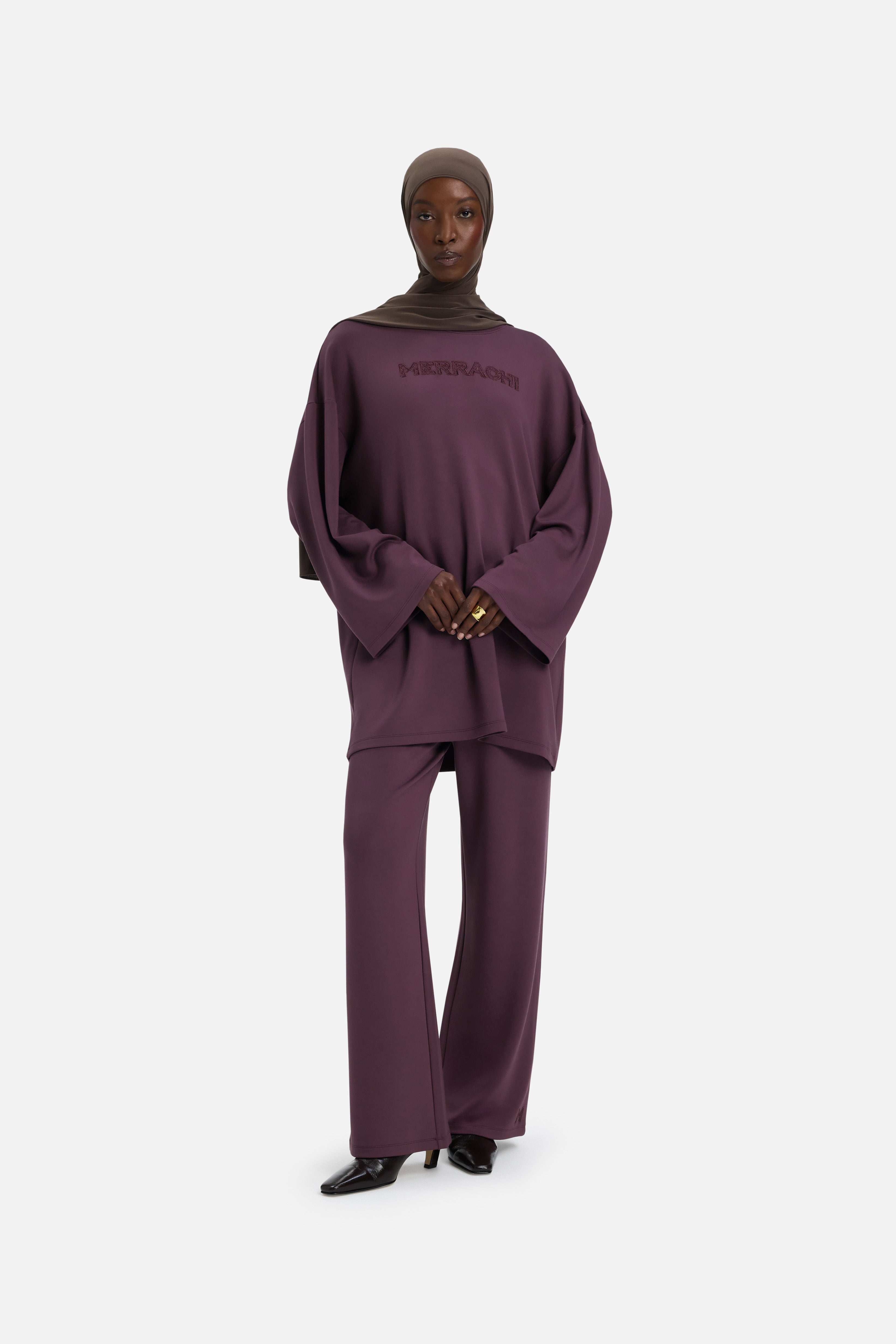 Model wearing purple MERRACHI pants, front view