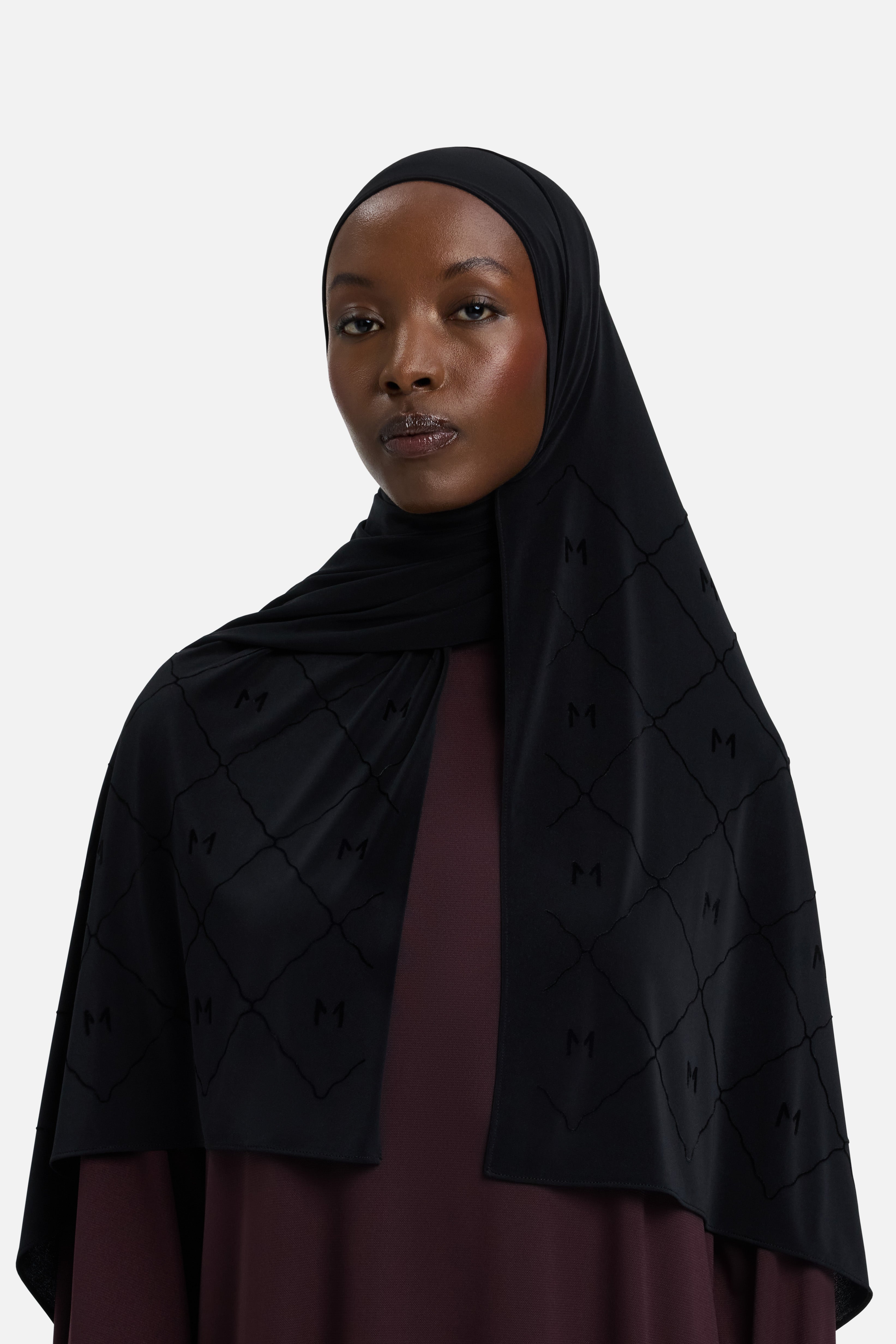 Model wearing black headscarf MERRACHI logo and embroidery, side view