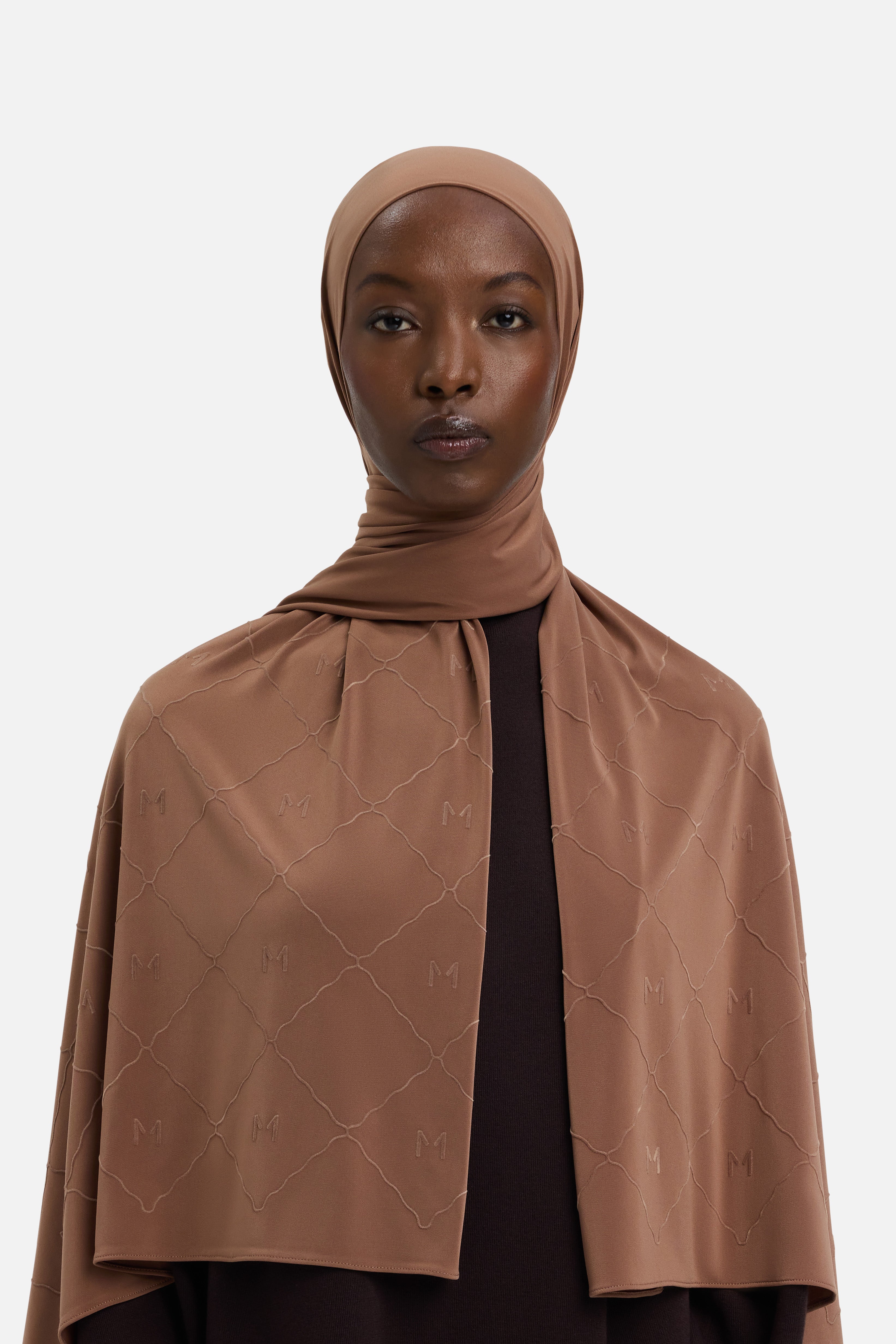 Model wearing brown headscarf MERRACHI logo and embroidery, front view