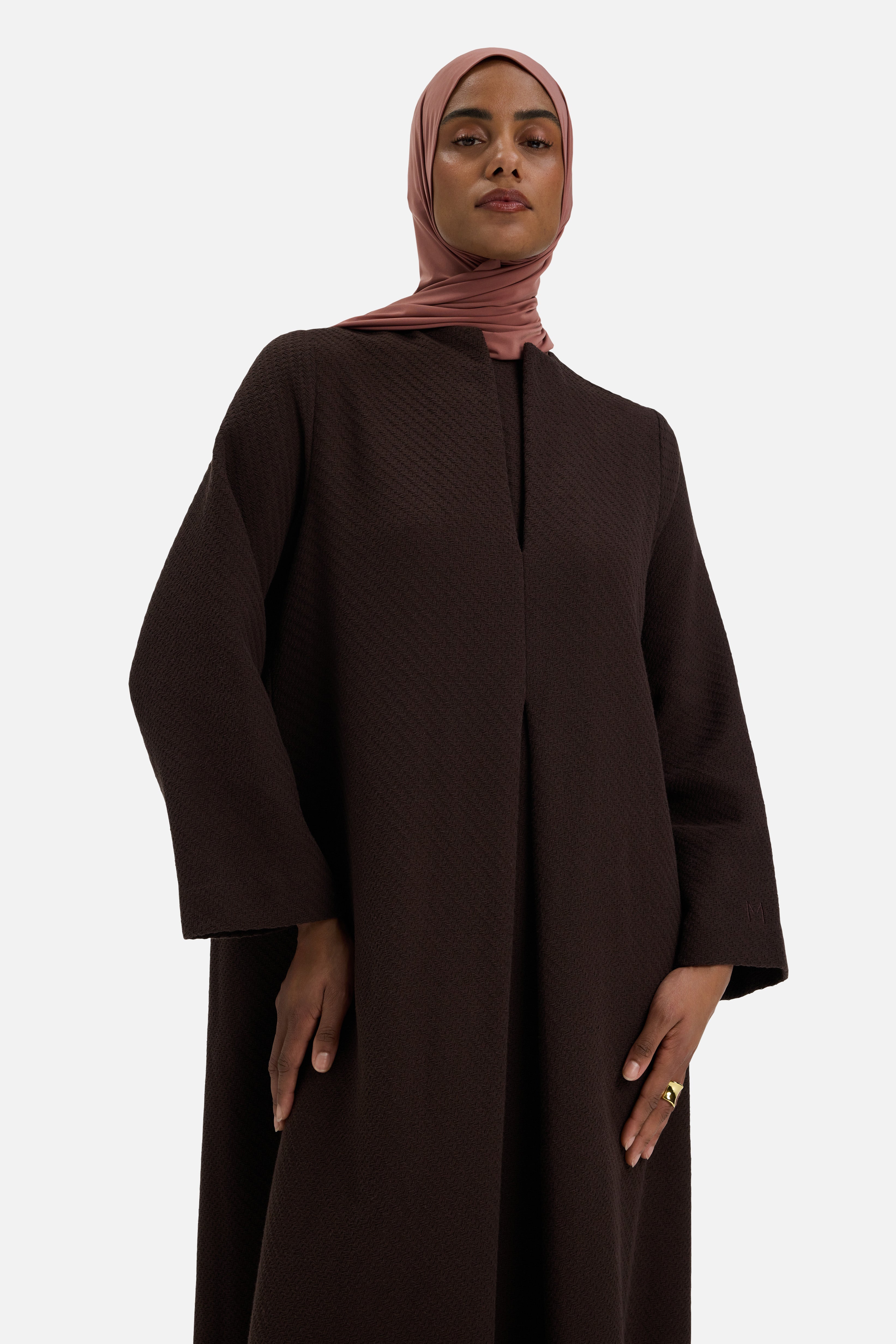 Detail view model wearing dark brown dress and pink headscarf