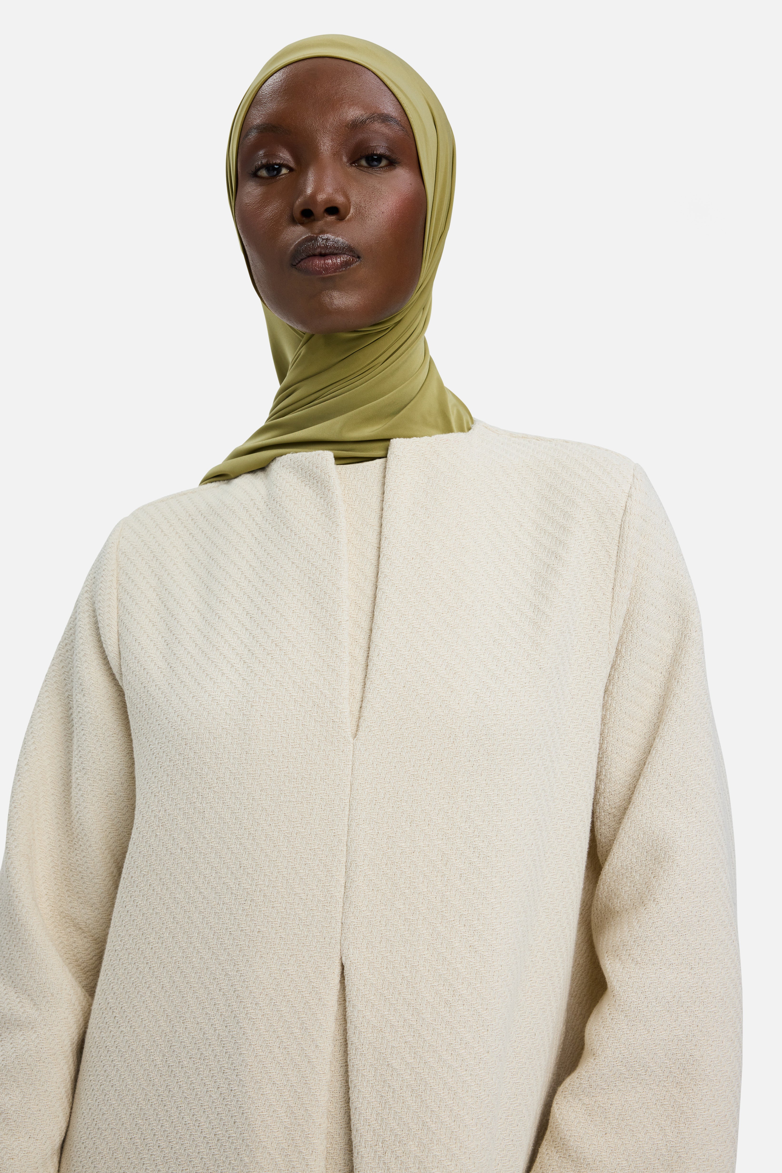 Close up model wearing off white dress and green headscarf