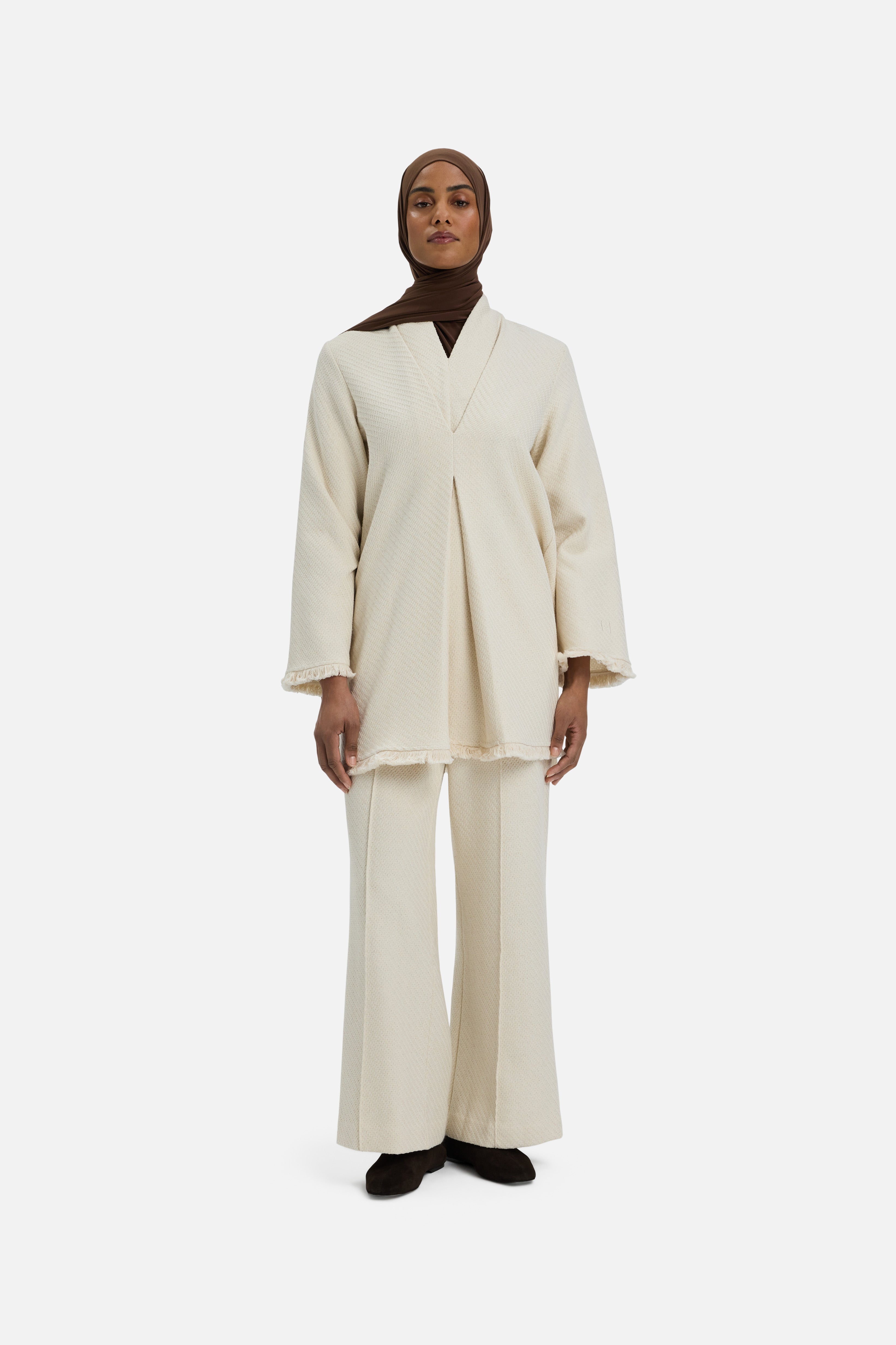 Front view model wearing white trousers and brown headscarf