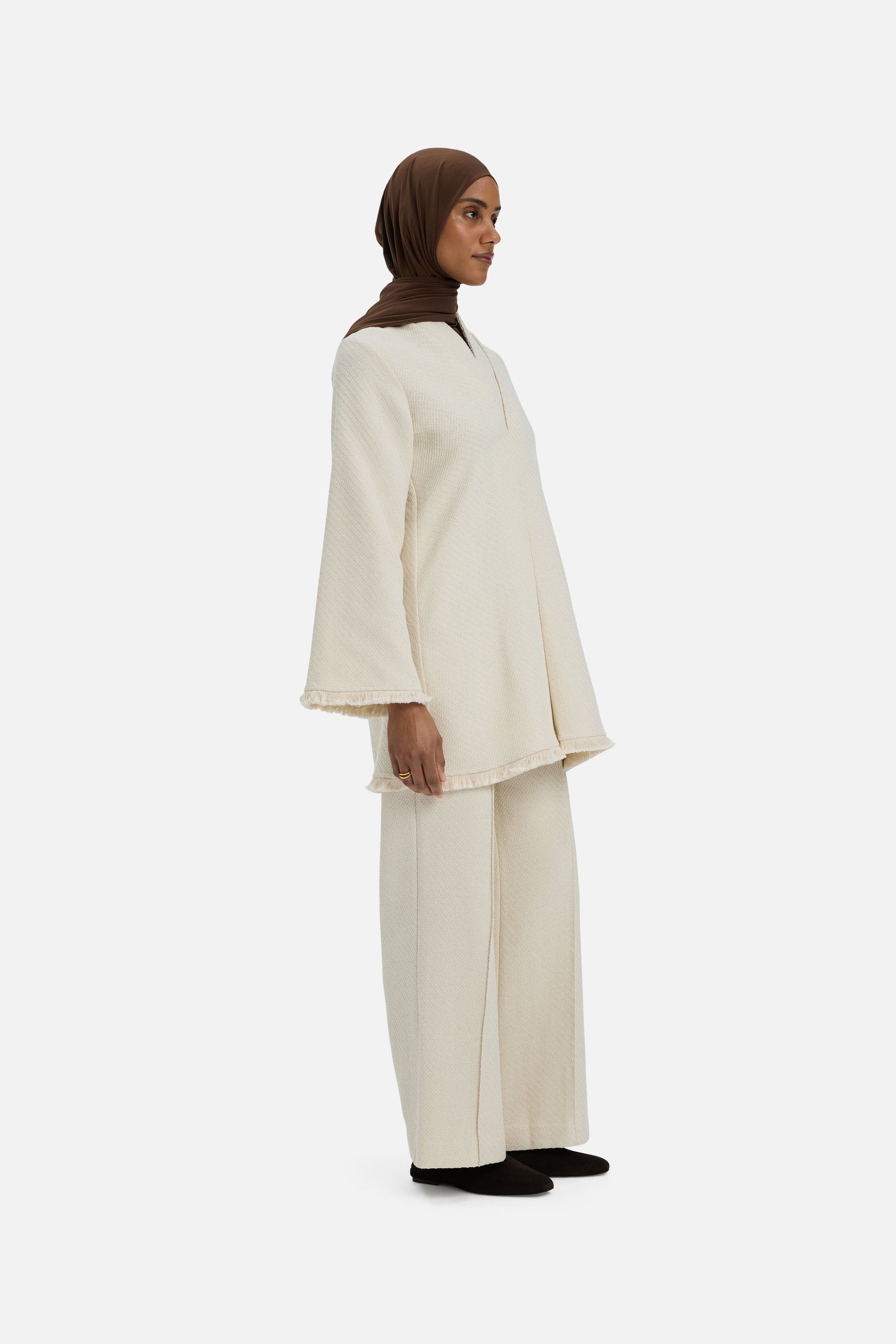 Front view model wearing white trousers and brown headscarf