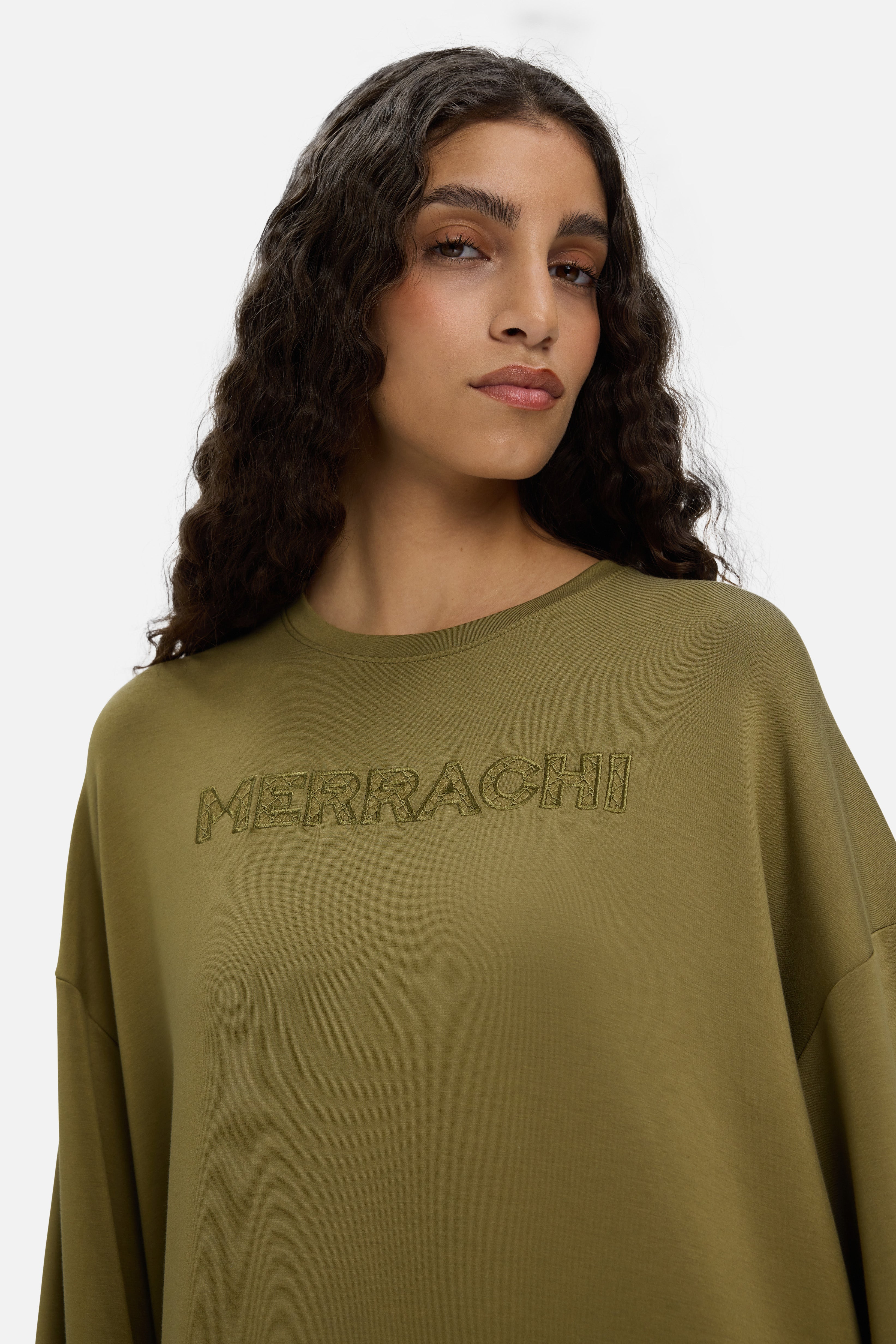 Model wearing green dress with MERRACHI embroidery