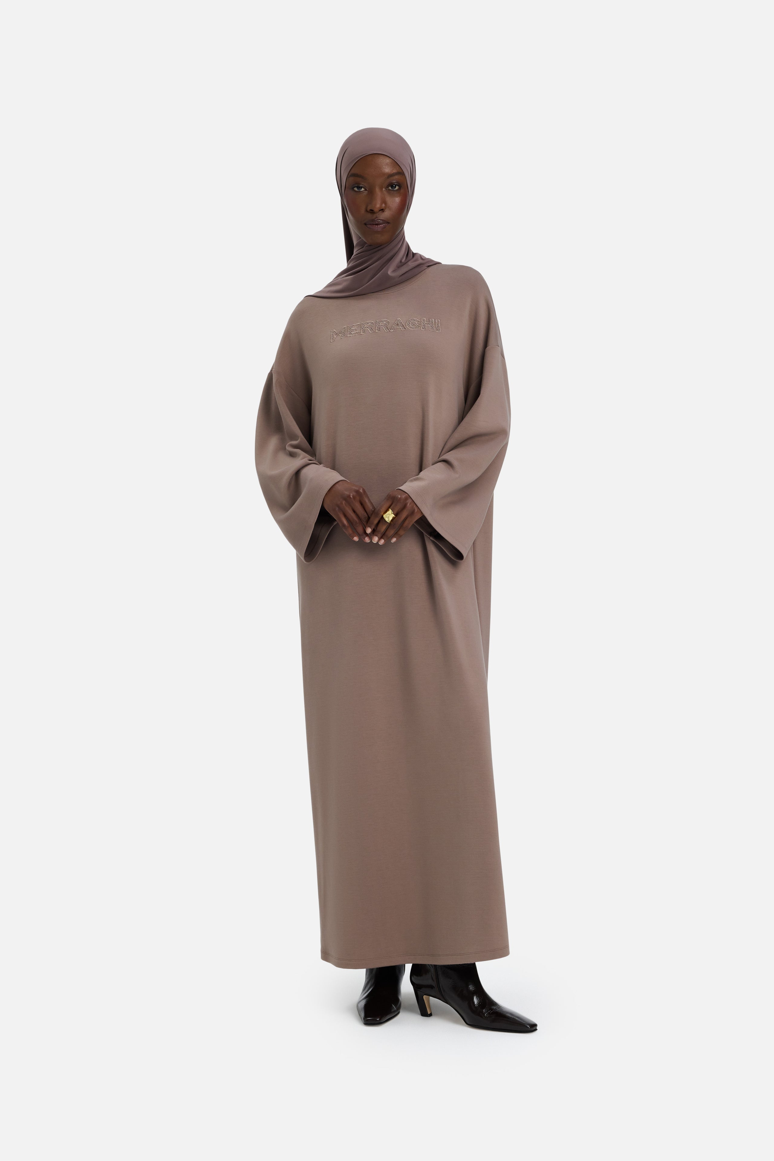 Model wearing modest taupe dress and headscarf, front view
