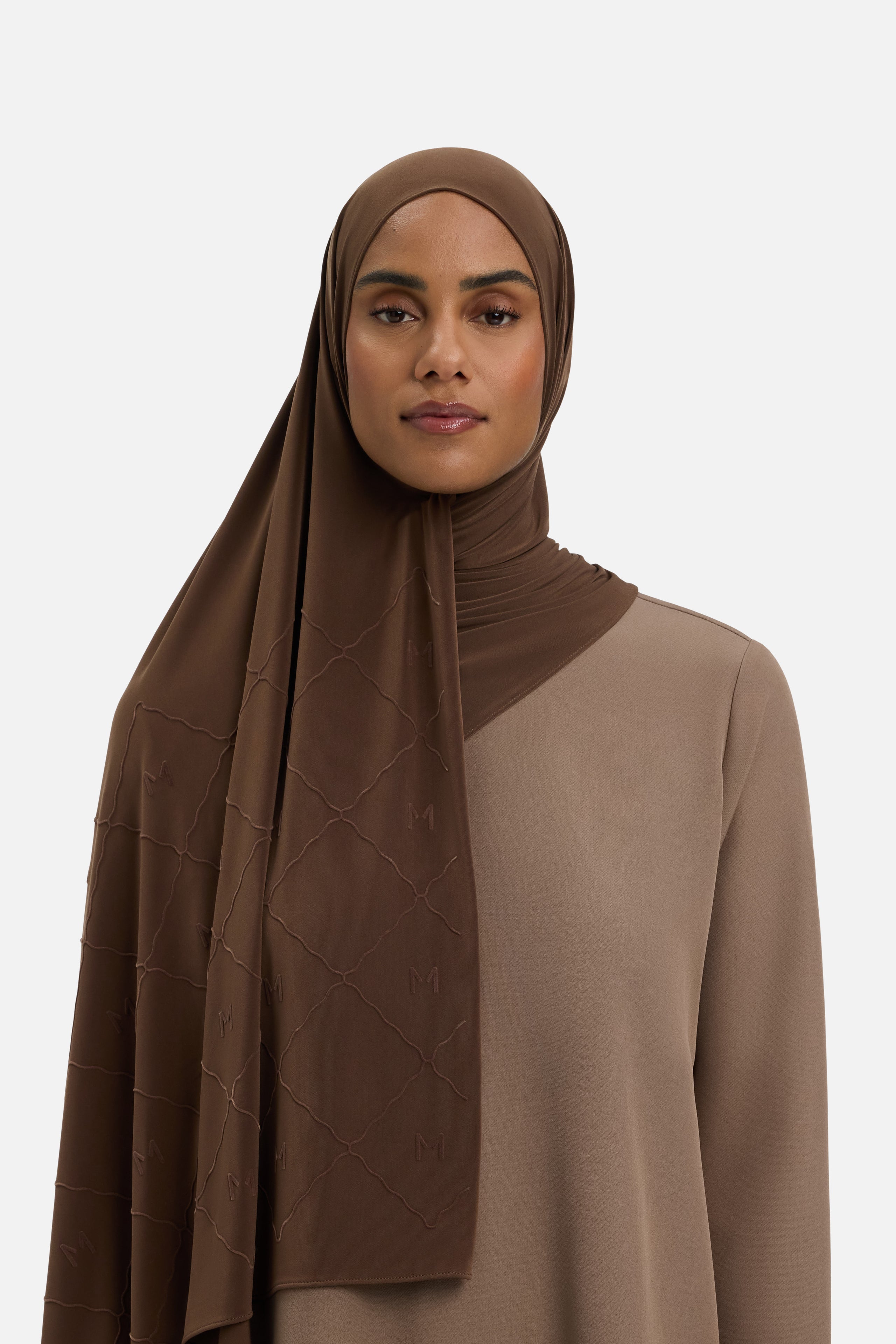 Model wearing dark brown headscarf MERRACHI logo and embroidery, front view