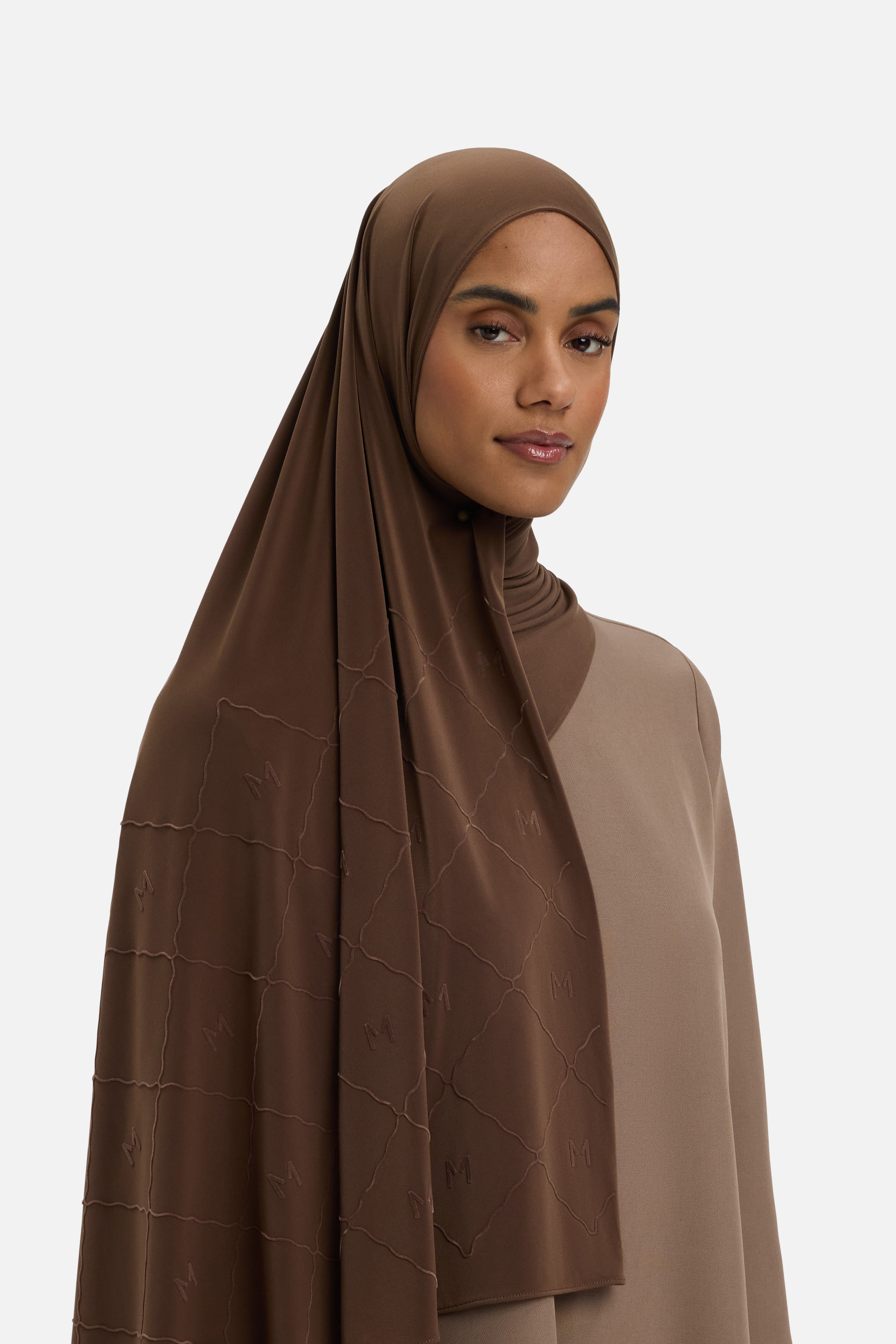 Model wearing dark brown headscarf MERRACHI logo and embroidery, front view