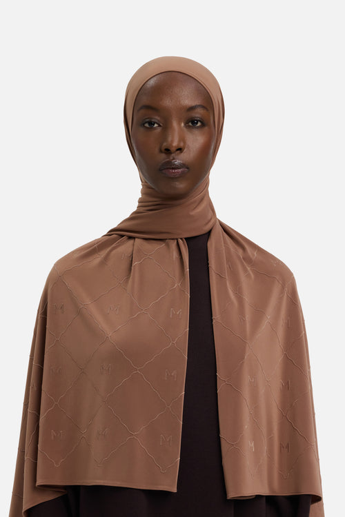 Model wearing brown headscarf MERRACHI logo and embroidery, front view