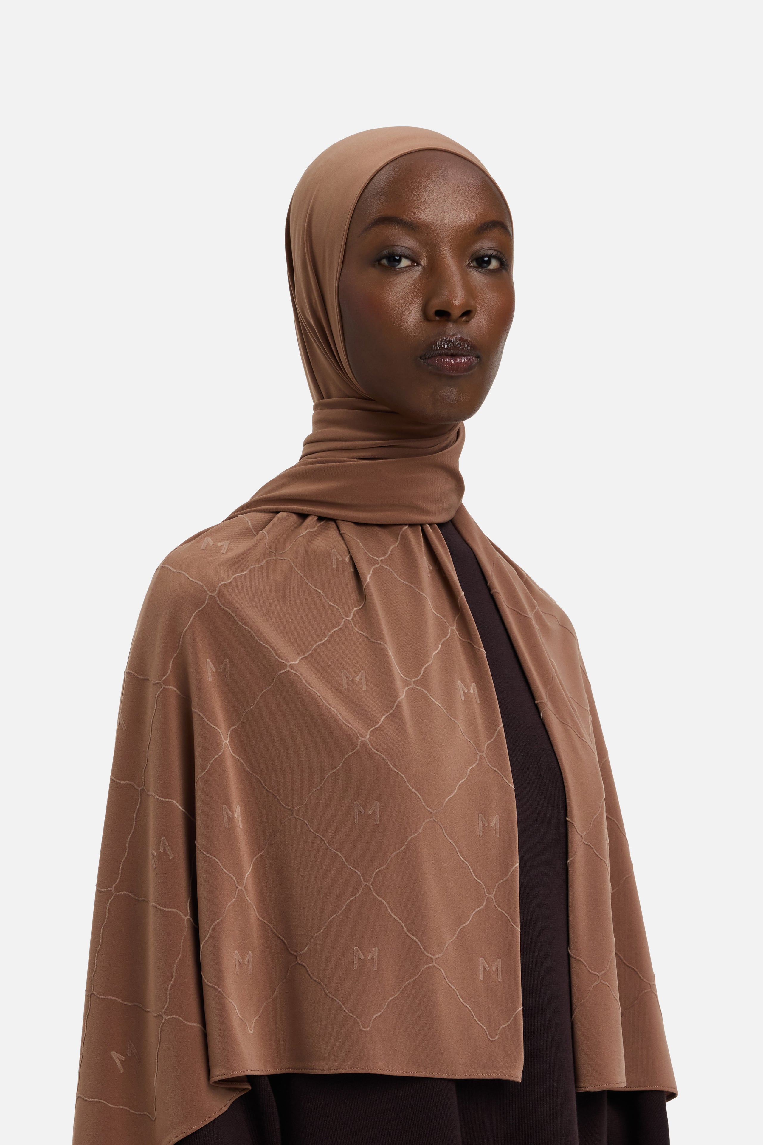 Model wearing brown headscarf MERRACHI logo and embroidery, front view